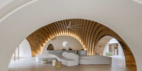 A modern hotel lobby that includes curved walls, hanging planes of bamboo, and hidden lighting that highlights the design. Modern Hotel Lobby, Chalet Interior Modern, Tropical Interior Design, Midcentury House, Hidden Lighting, Chalet Interior, Bamboo House, Traditional Houses, Architecture Building Design