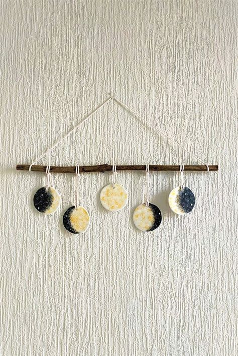 This is a wall hanging air-dry clay decoration. To make it, I used DAS air-dry clay, acrylic paint, a string and a wooden stick I found outside. This project is fun and easy to make, so you should give it a go! Moon Phase Craft, Air Dry Clay Moon Phase Diy, Moon Phase Hanging Decor, Gold Moon Phase Wall Hanging, Boho Wall Art Moon Phase, Wall Hanging Diy, Moon Phases, Air Dry Clay, Decor Project