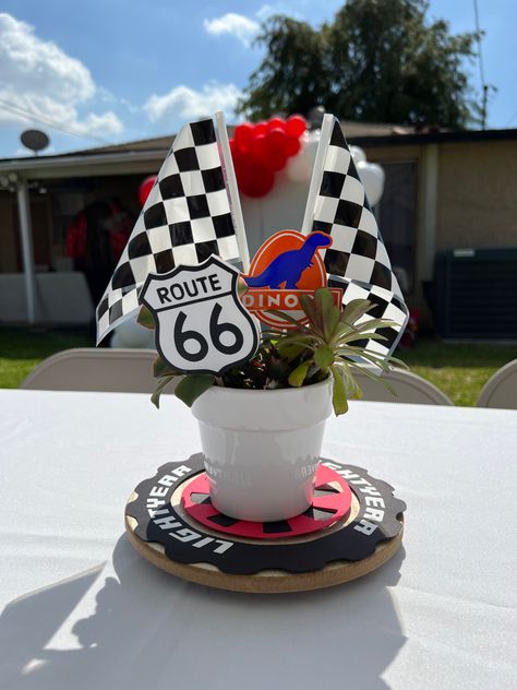 Potted succulents with race car flags and route 66 sign as a Cars theme centerpiece. Disney Cars Theme Centerpiece Ideas, Racecar Theme Centerpieces, Cars Disney Centerpieces, Racecar Party Centerpieces, Car Theme Centerpieces, Nascar Centerpiece Ideas, Car Birthday Centerpieces, Car Party Centerpiece, Two Fast Centerpiece Ideas