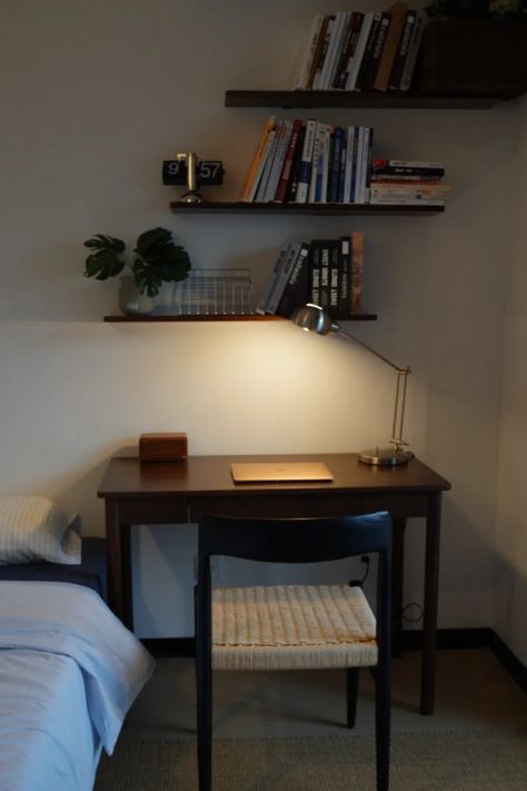 A minimalist dark wood desk with a modern table lamp, a laptop, and retro-style decor. Floating shelves hold books and plants, adding to the cozy and functional setup. This compact workspace is perfect for small spaces and a relaxed, focused environment. Simple Desk Setup Small Spaces, Writing Desk Setup, Small Desk Setup Ideas, Small Desk Setup, Minimalist Desk Setup, Bedroom Desk Organization, Small Bedroom Desk, Dark Desk, Dark Wood Bedroom