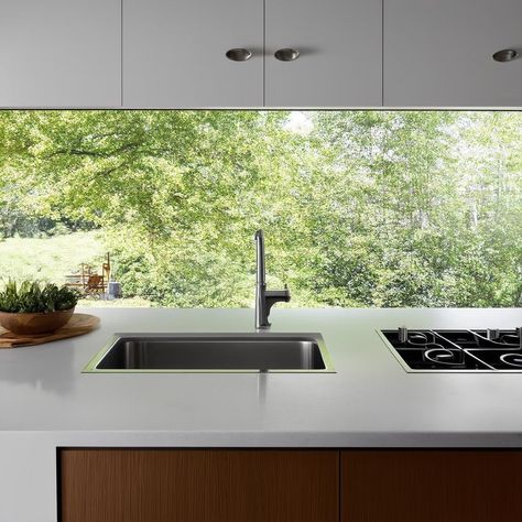 A modern kitchen with a large glass backsplash offering a stunning view of the outdoors, creating a seamless connection between the kitchen design and the natural landscape outside.