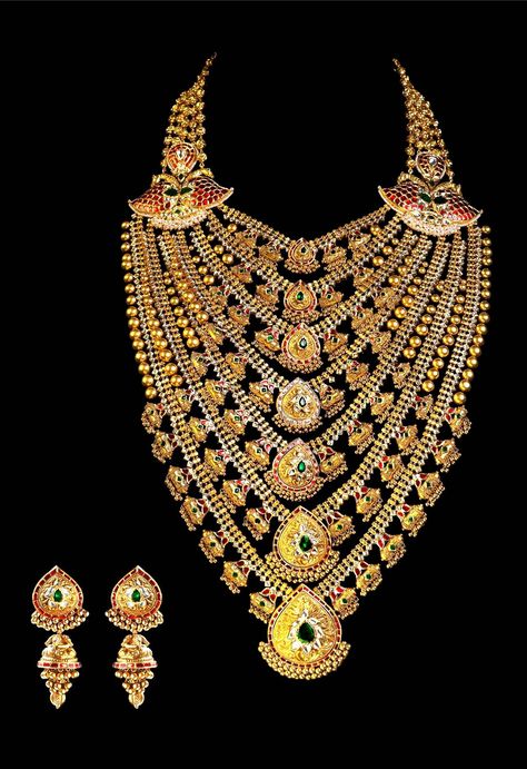 Mughal inspired bridal set from Gujarati and Rajasthani heritage. It comprises of seven rows of golden chains, festooned with gold pendants in different sizes, with highlights of red and green. Its centerpiece is called a Sita haar. It is also adorned with Indian jewellery staples; ambis, ghunghroos, golden beads. The capsule pieces, madaliya and the gold with white stones. In the Mughal era, jewellery was indication of one’s wealth, power, influence and taste. Rajhistani Jewellery, Rajasthani Gold Jewellery, Mughal Jewellery, Victorian Jewelry Necklace, Mughal Jewelry, Indian Gold Necklace Designs, Gold Souk, Flower Jewelry Designs, Multilayer Necklace