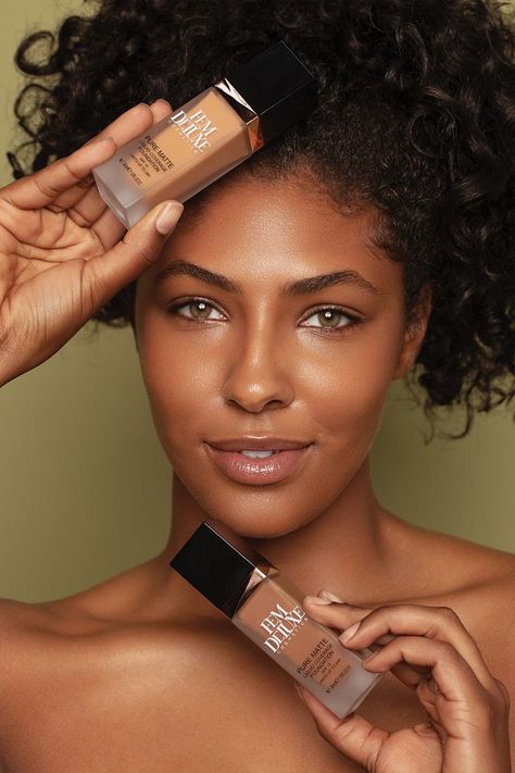 An African American woman is pictured from the shoulders up. She has curly, dark brown hair is styled up high. She is looking straight forward with her right hand resting on her head holding a lighter toned foundation. Her left hand is held below her chin and it is holding a darker tone foundation. Product Photography Model, Foundation Aesthetic Photography, Make Up Campaign Photography, Cosmetics Photography With Model, Foundation Photoshoot, Foundation Product Shoot, Cosmetic Photoshoot, Skincare Commercial, Dark Skin Foundation