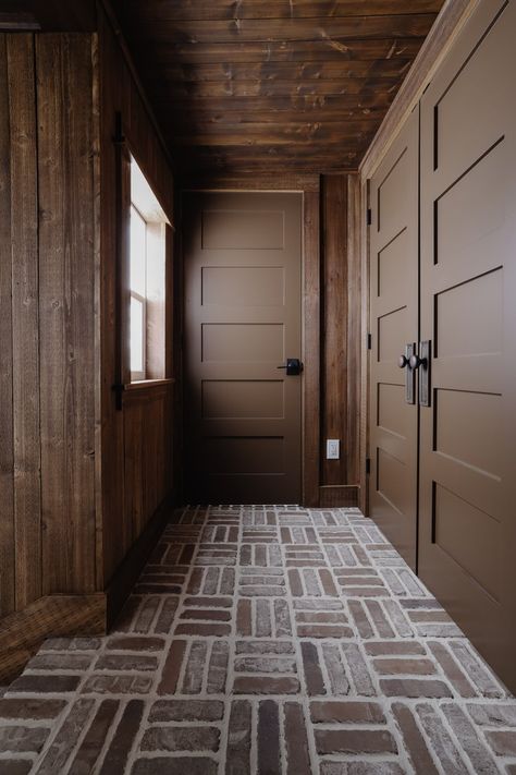 Laundry Room Off Hallway, Mudroom Dutch Door, Dark Brown Laundry Room, Rustic Wood Walls Living Room, Dark Laundry Cabinets, Rustic Cabin Laundry Room, Mud Room Flooring Ideas, Dark Wall Panelling, Moody Brown Paint Colors