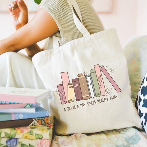 Indulge your bookish side with our charming Book Lover Tote Bag. Crafted from durable 100% off-white cotton canvas, this tote features a spacious, open design with a wide-mouthed opening for easy access to your essentials. The 1" cotton canvas handles are reinforced for added strength, ensuring comfortable carrying wherever your literary adventures take you. Design: Our Book Lover Tote Bag showcases a delightful book-themed design making it a stylish accessory for any bookworm. Whether you're heading to the library, bookstore, or simply running errands, let your love for literature shine with this eye-catching tote. Size: One Size - 16" tall x 15" wide Care Instructions: To keep your tote looking its best, spot wash with a warm soapy cloth and hang to dry. Please refrain from placing it in Bookish Tote Bag, Book Themed Gifts, Gifts Book, Library Bag, Best Tote Bags, Painted Tote, Book Tote Bag, Girls Tote, Dream Gift