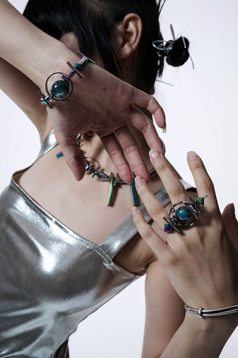 Experience the perfect fusion of futuristic vibes and avant-garde flair with our Planet Beaded Bracelet. At its center, the bracelet features a metal sphere surrounded by circular rings, resembling a celestial body. Interspersed along the bracelet are several elongated cylindrical beads, reminiscent of thorns, adding a touch of edginess to the design. In addition to the metal elements, the bracelet also features beads that reflect neon lights, creating a mesmerizing and futuristic effect. Crafte Scifi Accessories, Cyberpunk Bracelet, Rajni Perera, Space Oddessy, Future Accessories, Futuristic Accessories, Concept Jewelry, Futuristic Jewelry, Metal Sphere