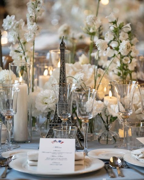 A Parisian-inspired wedding table setting with white flowers, candles, and a miniature Eiffel Tower centerpiece. Eiffel Tower Wedding, Eiffel Tower Centerpiece, Floral Arrangement Wedding, Elegant Wedding Table, White Floral Arrangements, Wedding Table Setting, Parisian Wedding, Flowers Candles, Paris Inspired