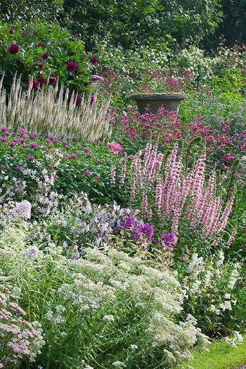 Delicate blooms in pink, white, and purple nearly cover the antique urn in this English garden at Wollerton Old Hall. Photo by Clive Nichols Garden Photography. Cottage Garden Design, English Gardens, English Cottage Garden, Have Inspiration, Herbaceous Perennials, Cottage Gardens, Garden Photography, Garden Borders, Garden Care