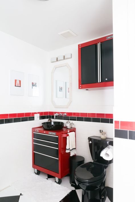 While black and red isn't the couple's preferred color palette, they chose to embrace the existing tiles and go for a full auto shop-inspired bathroom theme. Shop Bathroom Ideas, Man Bathroom, Couples Decor, Garage Bathroom, Mechanic Shop, Hit Or Miss, Automotive Furniture, Shop Bathroom, Auto Shop