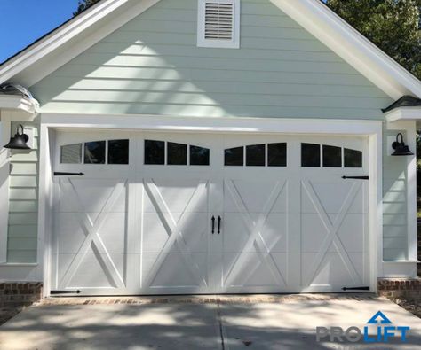 This white, carriage house garage door has the look of painted wood and has the charm of an old fashion barn door but is designed, instead, with today's high tech, low maintenance faux wood materials. Notice the decorative door handles, strap hinges, 'X' panel pattern and arched windows too! | Pro-Lift Garage Doors on Houzz | Photo Credits: Pro-Lift Garage Doors Savannah Garage Trellis, Garage Door Trim, White Garage Doors, Faux Wood Garage Door, Walpole Outdoors, Carriage House Garage Doors, Garage Door House, Carriage House Doors, Trellis System