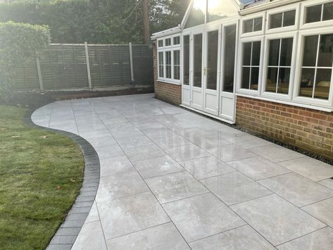 Sweeping, curved Porcelain patio with contrasting Granite Sett edging. #patioedging #patiodesigns Patio With Edging, Patio Design Ideas Uk, Curved Patio Design, Patio Edging Stones, Patio Edge Ideas, Garden Curved Patio Ideas, Curved Paver Patio Ideas, Porcelain Patio Edging Ideas, Porcelain Patio Ideas