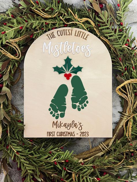 Never forget how little your baby's feet was with this adorable DIY Christmas keepsake! Add this to your Christmas decorations for many years to come! This baby mistletoes footprint sign also makes a wonderful gift for Grandma/Grandpa <3  Just add some paint (of your choice) to your little baby's feet and add to sign!  Sign is made with 1/4th inch baltic birch wood and with  1/8th acrylic!  Size is 8x10 inches  disclaimer* - since these are made using real wood, patterns and textures will differ and some knots and other inconsistencies that are present in wood, might show. Christmas Crafts With Baby Footprints, Baby Feet Christmas Ornaments, Christmas Gifts Made By Baby, First Christmas Footprint Craft, Baby Homemade Christmas Gifts, Christmas Baby Decorations, Christmas Craft Baby Footprint, Baby Christmas Keepsakes, Christmas Baby Feet Painting