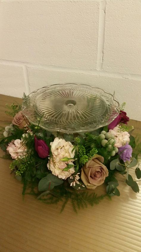 Cake Stand Table Centerpiece, Flowers Around Cake Stand, Cake Stand Flower Arrangement, Glass Cake Stand Decor Display, Cake Pedestal Ideas Display, Cake Plate Decor Display, Cake Stand With Flowers, Easter Cake Stand, Sheet Cake Stand