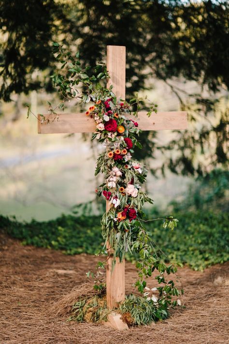 Wood Cross with a floral garland featured a mixed variety of foliage for texture and burgundy, rust oranges, and some light peach flowers. @anik_flowers; Laura Burchfield Events Ben;  Collen Wedding Photography Wedding Cross Altar, Flowers On Cross, Dekor Nikahan, Outdoor Wedding Altars, Wedding Core, Cross Flowers, Wedding Alters, Fun Wedding Decor, Wedding Isles