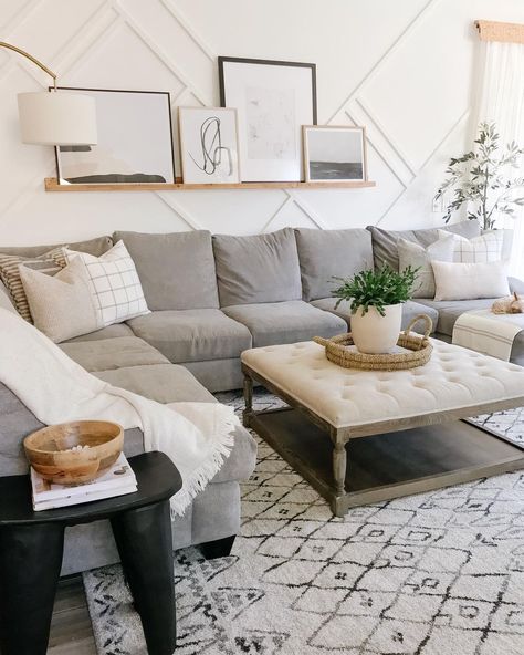 White and gray living room rug is laid under a wood and beige tufted ottoman coffee table for grey sectional couch. A light wood floating shelf is mounted above the sectional on a white wall with decorative molding. Jaci Daily, Dark Green Living Room, Grey Sectional Sofa, Simple Wall Decor, Dark Home Decor, Asian Home Decor, 3 Piece Sectional, Living Room Green, Living Room Decor Apartment