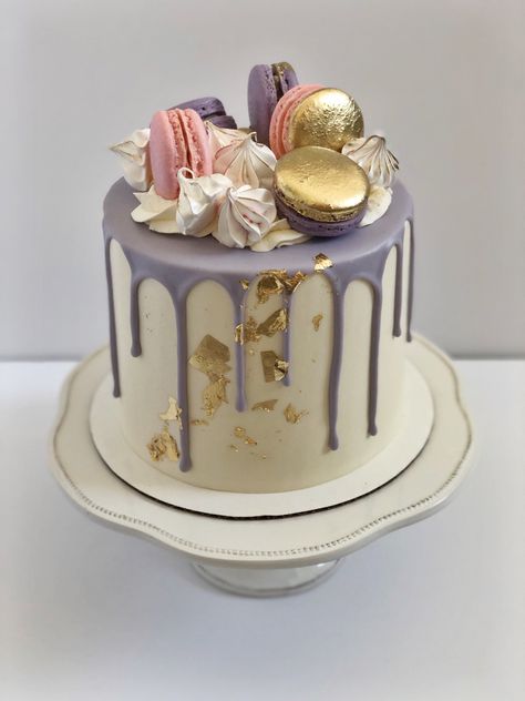 White cake with a purple drip and gold leaf details in front. On top there are purple and pink macarons with gold details painted on. There are also some meringues placed on top. Cakes Decorated With Macarons, Macarons Torte, Birthday Cake With Macarons, Purple Drip Cake, Birthday Cake Purple, Blue Drip Cake, Macaron Decoration, 21st Birthday Cake For Girls, Modern Birthday Cakes