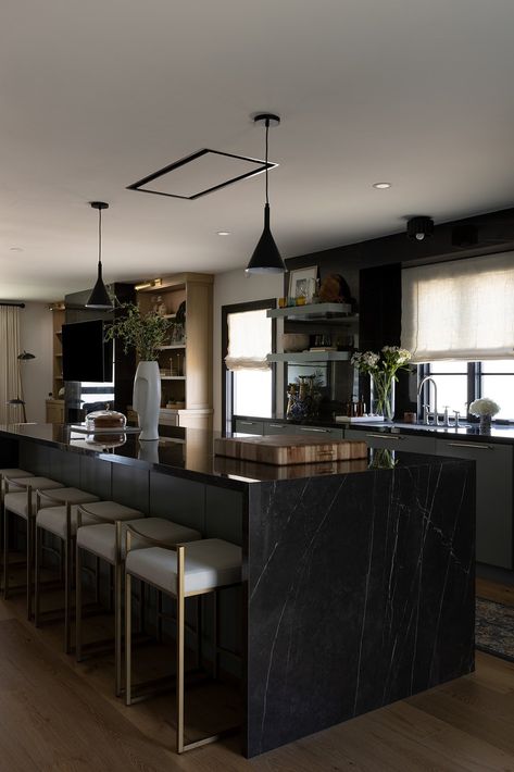 This sleek and sophisticated kitchen features a bold black marble waterfall island, brass-accented stools, and warm wood details to soften up the space. 🖤 Black Quartz Waterfall Island, Black Waterfall Island Kitchen, Black Waterfall Island, Black Marble Kitchen Island, Black Marble Island, Black Island Kitchen, Marble Waterfall Island, Studios Interior Design, Waterfall Island Kitchen