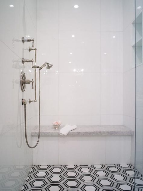 Walk-in shower features white, gray, and black hexagon floor tiles leading to a honed marble shower bench fixed against glossy white stacked shower surround tiles. Large Format Wall Tile, Marble Shower Bench, Black Hexagon Floor, Large White Tiles, Hexagon Floor Tiles, Ravenna Mosaics, Hexagon Floor, New Ravenna, Glass Shower Doors Frameless