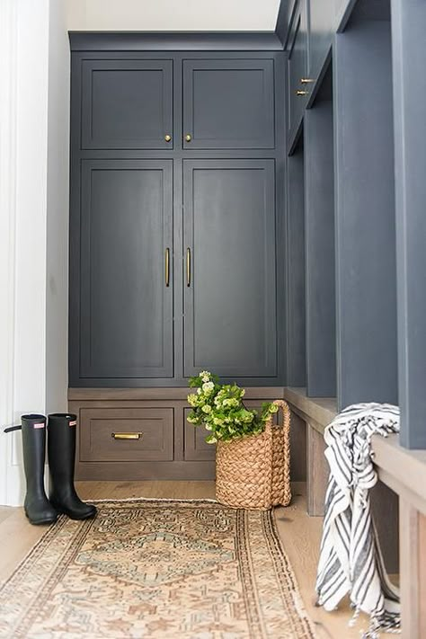 A+vintage+gold+and+blue+rug+sits+in+front+of+a+brown+oak+mudroom+bench+fitted+beneath+black+open+lockers+located+under+black+shaker+cabinets+donning+brass+knobs. Black Shaker Cabinets, Mudroom Cabinets, Laundry Room/mud Room, Casa Clean, Mudroom Lockers, Mudroom Entryway, Mudroom Decor, Mudroom Laundry Room, Mudroom Design