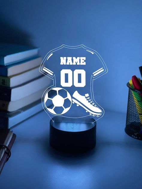 A creative and unexpected gift to that special person who loves Soccer! This charming Personalised Soccer Jersey 3D Night Light creates a visual emphasis in the interior of your bedroom, living room, gaming room, kids room, office, shop, bar, or creative space.  Night lights are perfect for home décor and will also be great for children who are afraid or just dislike to sleep in the dark. Table... Football Led Light, Soccer Boyfriend Gifts, Soccer Basket Ideas Gift, Soccer Gifts For Boyfriend, Football Kids Room, Living Room Gaming, Personalized Football Gifts, Laser Cut Lamps, Dark Table