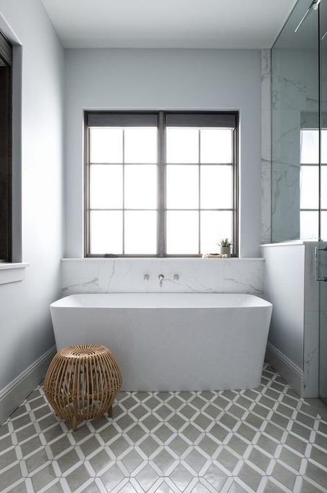 Place on white and gray lattice bathroom floor tiles, a rectangular freestanding bathtub sits beneath a wall-mounted tub filler fitted under a window. Bath Under Window, Bathroom Design Black, White Fireplace, Bathroom Tub, Standing Bath, Freestanding Bathtub, Guest Bathrooms, Bathroom Windows, Bathroom Floor Tiles