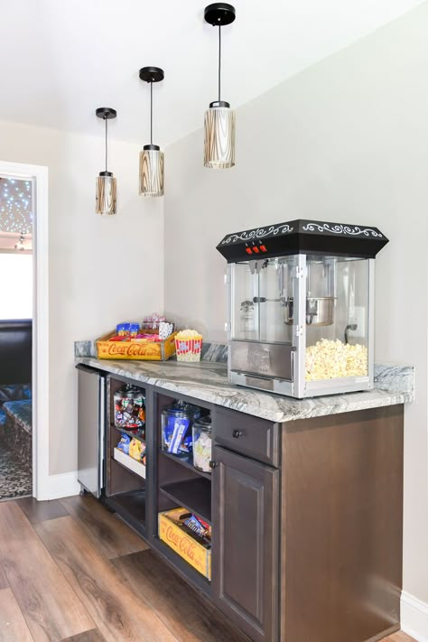 Elevate your home theater experience with a delightful popcorn and candy bar! 🍭🎥 Fill it with an assortment of snacks and sweets to satisfy every craving. Whether it's movie night or a casual get-together, this bar makes every occasion a little more special.   Photography | Mary Pat Collins Photography  #CandyBar #PopcornStation #HomeTheater #SnackBar #EntertainmentArea #PartyIdeas #TwoNavyLane Home Snack Bar Ideas, Basement Snack Bar Ideas, Movie Room Snack Bar, Movie Room Snack Bar Ideas, Basement Movie Room Ideas, Snack Bar Ideas Home, Movie Snack Bar, Home Theater Snack Bar, Popcorn Station