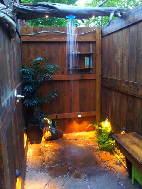 outdoor shower we built out of repurposed lumber. 1950 garage door, also drift wood logs, and sandstone rock found in a pile. Cabin Outdoor Shower Ideas, Pallet Shower Outdoor, Outdoor Shower Sauna Combo, Outdoor Cabin Ideas, Outdoor Shower Rustic, Boho Outdoor Shower Ideas, Outdoor Shower House, Beach Outdoor Shower Ideas, Outside Toilet Ideas Outdoor Bathrooms