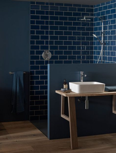 This stylish bathroom set-up featuring brassware from VADO uses dark blue tiles to create a moody, relaxing aesthetic. The use of wood for the flooring and vanity unit adds a welcoming warmth to the overall design. #BlueBathroom #BlueTiles #StatementBathroom #BathroomDesign #InteriorDesign Blue Tiled Bathroom, Dark Blue Rooms, Dark Blue Tile, Dark Blue Bathrooms, Moody Bathroom, Tiled Bathroom, Blue Bathroom Tile, Shower Columns, Bath Shower Mixer Taps