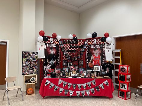 School colors: Red, Black, & White. We built a background with Lattice and painted it Red. I purchased the “Soccer” , “Basketball” , and “Baseball” signs from Hobby Lobby, then painted them black. I purchased the 5x7 picture frames from dollar tree. I used floral wire and attached them all together. They are 5x7s from 5K to 12th grade. I purchased the numbers from hobby lobby and painted them white. I purchased the grad boxes from Amazon. I purchased the black chalkboard buckets from Hobby Lobby Rustic Senior Table, Senior Display Table Ideas For Sports, Senior Cheerleader Table Ideas, Senior Night Table Display Cheer, Graduation Sports Display, Cap And Gown Display For Party, Senior Sports Boards, Jerry Graduation, Senior Baseball Table Ideas