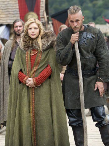 Here Lagertha wears a bilberry-dyed lime green cape and an orange woolen maternity dress. Her husband Ragnar (Travis Fimmel) wears black leather pants and an elaborated molded, decorated black leather vest emblazoned with his insignia -- the raven -- that symbolizes his descent from the great Norse god Odin, also a god of slain warriors and curiosity. Vikings Series, Clothes Dye, Viking Series, Vikings Tv Show, Vikings Tv Series, Vikings Ragnar, Viking Dress, Alexander Ludwig, Bright Outfits