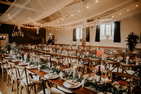 Ceiling Draping Festoon Lighting Wooden Cross Back Chairs Greenery Tables Willingale Village Hall Wedding Photographer Liam Gillan  #weddinggreenery #greenerywedding #tablesettings #tablerunner #tabledecor #weddingdecor Indoor Draping Wedding, Hall Wedding Decor, Hall Wedding Decorations, Wedding Drapes, Reception Ceiling, Wedding Ceiling Decorations, Ceiling Drapes, Wedding Reception Hall, Village Hall Wedding