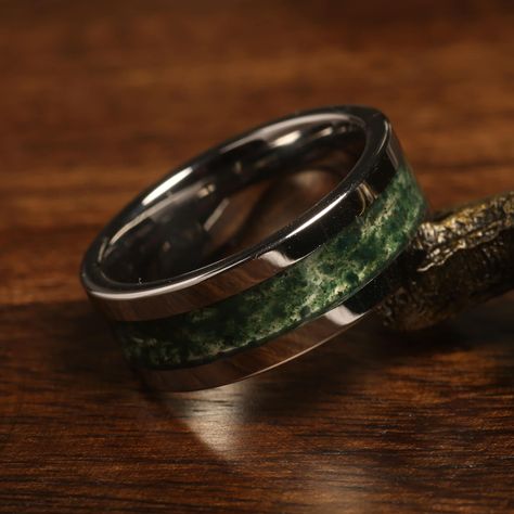 "Elevate your special moments with our stunning Green Moss Agate Tungsten Ring. This unique piece is not just a symbol of commitment but a statement of individuality and style. Crafted with high-quality black tungsten, this ring features a mesmerizing green moss agate inlay that showcases the beauty of nature. As a unisex ring, it offers versatility for both men and women seeking an extraordinary wedding band, anniversary token, or an engagement or promise ring. The black tungsten band provides Luxury Men's Green Ring With Accent Stones, Tree Ring Men, Mens Wedding Ring Cool, Male Promise Rings Stone, Earthy Wedding Rings For Men, Mens Wedding Rings Gay Friendly, Men's Wedding Rings Vintage, Wedding Rings Men Vintage, Witchy Wedding Rings Mens