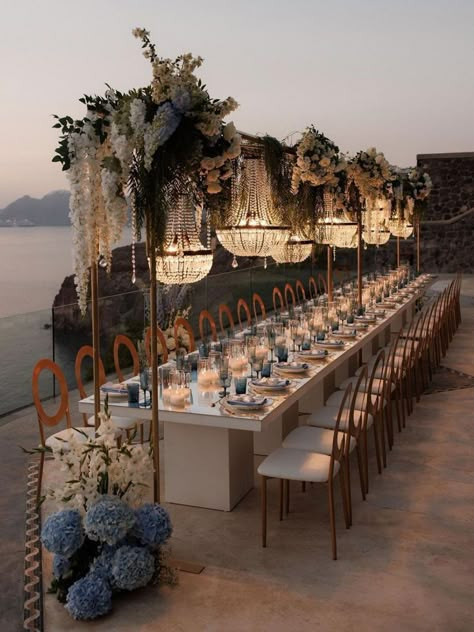 Elegant florals, crystal chandeliers & breathtaking views make this wedding reception unforgettable | wedding, wedding inspo, wedding planning, wedding reception decor, wedding reception ideas, wedding reception decor, intimate wedding, destination, wedding, Santorini, Santorini wedding, luxury wedding reception, wedding tablescapes, wedding table decor, wedding flowers, wedding table centerpieces, summer wedding, blue wedding, something blue wedding #weddingreception #summerwedding #Santorini Outdoor Wedding With Chandelier, Wedding Arab, Villa Wedding Reception, Summer Wedding Blue, Engagement Setup, Greek Islands Wedding, Wedding In Greece, Destination Wedding Decor, Europe Wedding