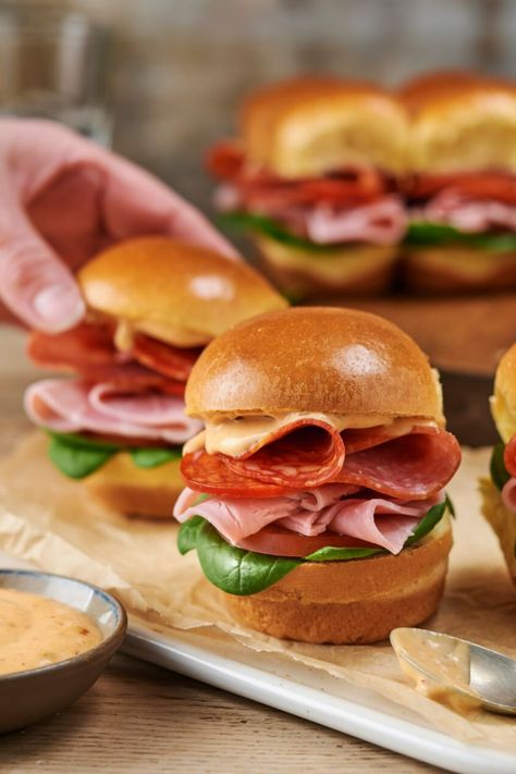 A close-up of brioche slider rolls filled with meats on a wooden board, with a hand picking one roll up. Mini Sliders Recipe, Salami Lunch Ideas, Mini Subs, Brioche Sliders, Mini Brioche Sandwiches, Brioche Sandwich, Deli Ham Recipes, Mini Blt, Sandwich Inspiration