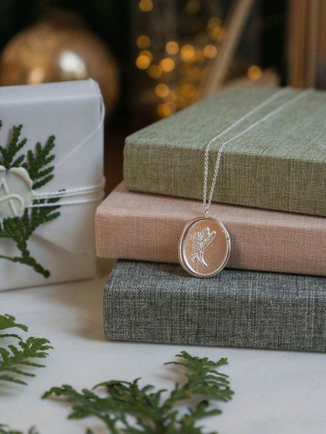 Photo of a silver necklace with a birch design on it. The necklace is laid out on some books with twinkle lights in the background and cedar. Christmas Jewelry Packaging, Christmas Jewellery Photoshoot, Winter Jewelry Photoshoot, Christmas Jewellery Photography, Christmas Jewelry Photography, Winter Accessories Jewelry, Christmas Product Photoshoot, Jewellery Shots, Earring Photography