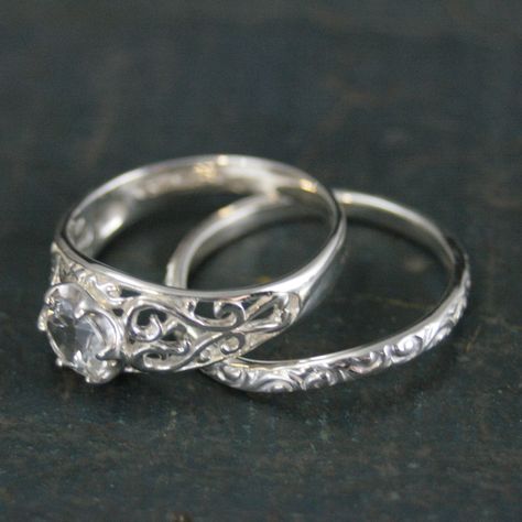 This antique-inspired silver bridal set evokes a tale of destined love.  Intricate filigree vines gracefully adorn the shank, cradling a 6mm sparkling Sleeping Beauty moissanite in a stunning sweetheart setting. A true fairytale engagement ring, perfect for saying "I know you. I've walked with you once upon a dream." Silver Antique Wedding Ring, Silver Engraved Engagement Ring, Wedding Ring Inspiration Silver, Hippie Engagement Ring Silver, Antique Silver Engagement Rings, Unique Engagement Ring Silver, Alternative Wedding Rings Silver, Vintage Silver Wedding Rings, Engagement Rings Silver Vintage