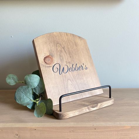 This rustic yet elegant cookbook stand adds charm to anyone's kitchen.  A perfect gift for any cook!  Customizable with vinyl lettering and a clear polyurethane added on top.  Specifications: - Handcrafted from solid pine - Choose from 4 stains, shown in walnut with gold - Metal bar detail available in black or gold - Approximately 9" Wide x 11" Tall Instagram @267company www.267company.ca ~ Colours~ Each item is handcrafted and made to order so item may look slightly different than the picture Wood Cookbook Stand, Recipe Book Holder, Recipe Book Stand, Recipe Book Holders, Cookbook Stand, Bar Detail, Cookbook Holder, Cook Book Stand, Carpentry Projects