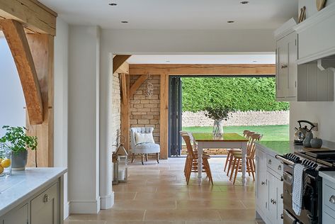 The 6m wide opening for the door to the garden are a real feature that required us to work closely with our structural engineer to arrive at a solution to ensure such a span is possible in oak. The result is worth the head scratching and ensures a seamless link from the well maintained family garden and into the kitchen beyond the original house #stroud #cotswolds #gloucestershire #oakframe #extension #homeinspo #luxuryhome #design #selfbuild #architecture #home #house #timber #cosy #luxury Wood Cladding Interior, Oak Shelving Unit, Blue Shaker Cabinets, Reclaimed Kitchen, Oak Framed Extensions, Oak Worktop, Slate Floor, Bungalow Renovation, Open Plan Kitchen Living Room