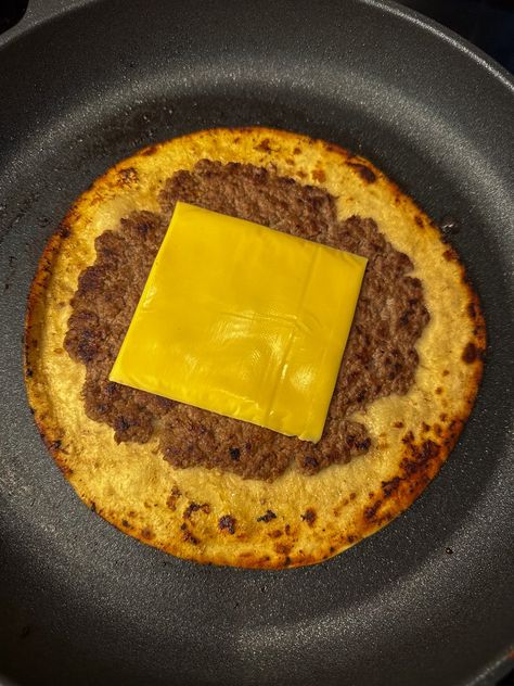 Slice of American cheese melting in the center of a freshly smashed burger on a golden brown tortilla shell in a black non-stick skillet. Hamburger On Tortilla, Flour Tortilla Smash Burger, Hamburger Smash Tortilla, Hamburger Tortilla, Smash Burger Tortilla, Taco Smash Burgers Tortilla, Tortilla Hamburger Smash, Tortilla Smash Burger Taco, Smashed Burgers On Tortillas