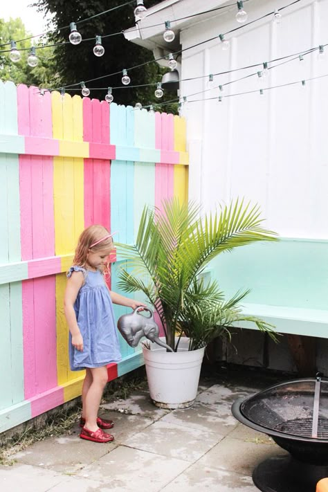 Our Backyard Patio Makeover Colourful Fence Ideas, Colourful Garden Fence, Rainbow Fence Backyards, Diy Fence Mural, Funky Backyard Ideas, Coloured Garden Fence, Colorful Fence Ideas, Backyard Fence Painting Ideas, Colourful Fence