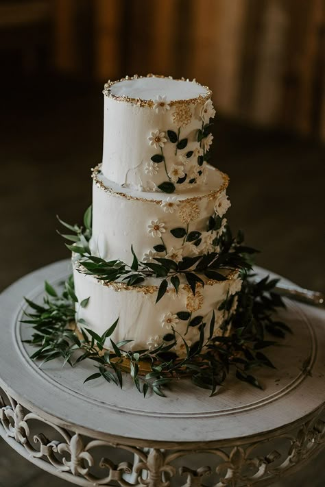 White three tier rustic wedding cake with iced flowers and green foliage Wedding Cakes With Black, Wedding Cakes Green And White, 3 Tier Wedding Cake With Greenery, Boho Wedding Cake Sage Green, Wedding Cake Three Tier Flowers, Camp Wedding Cake, Forest Fairy Wedding Cake, Green Theme Wedding Flowers, Wedding Cakes Dark Green