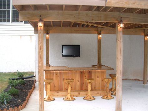 Royersford, Pa.  8x5 custom red cedar tiki bar, I custom fit this tiki bar under his deck and incorporated the support poles from his deck into the bar. There is electric, cable tv, 3 outlets, fridge, rope lighting, 6 bar stools, solid cherry bar top, lower bar top and cabinets. Full photo album can be seen here on facebook - https://www.facebook.com/tikikev/photos_albums . For more info go to www.tikikev.com or contact me directly at 800-792-8454 , or email to tikikev@tikikev.com Bar Under Deck, Outdoor Deck Decorating, Under Deck, Outdoor String Lights Patio, Deck Bar, Play Area Backyard, Cedar Deck, Porch Bar, Indoor Lights