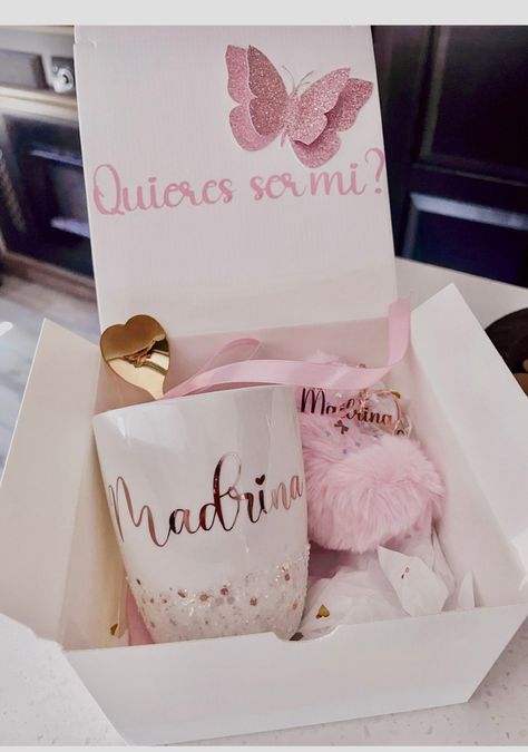 Hermosa caja de regalo para una futura Madrina.                                                                                                                                                                               Que incluye la caja de Madrina?                                                                                                              1- Incluye una caja de regalo con un mensaje, Quires ser mi? [ Se puede personalizar el mensaje si desea Será un costo adicional]                                                                                                                                                     2- Una hermosa taza color blanco con glitter en el borde y la palabra Madrina con un diseños en color Metalico color rose gold.[Los diseños son hechos en vinil Madrina Box Ideas, Will You Be My Madrina Ideas, Padrino Proposal Ideas, Madrina Proposal Ideas, Godparent Request Ideas, Godparent Request, Pink Dinosaur Party, Baby Boy Baptism, Baby Shawer