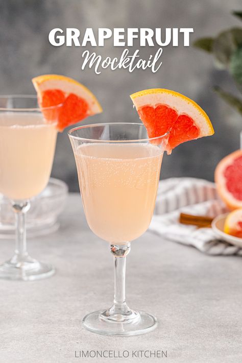 Side view of two Grapefruit Mocktails in goblet style wine glasses on a gray countertop, each with a quarter slice of grapefruit as a garnish on the rim of the glass. Cut fresh pink grapefruit is in the background on the right along with a gray striped linen, cinnamon sticks and some greenery in a vase. Text above the drinks reads “Grapefruit Mocktail”. Grapefruit Mocktail, Flavor Pairing, Citrus Drinks, Non Alcoholic Punch, Cinnamon Syrup, Dry January, Brunch Drinks, Grapefruit Juice, Mocktail Recipe