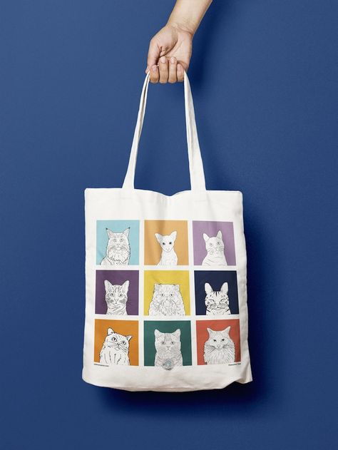 The image shows a tote bag being held by a long handle from the top of the photo, against a rich royal blue background. The tote back is white with a 3 x 3 9 image grid of brightly coloured squares. Each square is a different colour and features a black and white digital illustration of the head and shoulders of a different cat breed - ragdoll, shorthair, main coon, persian, moggy, tabby etc. Bright Bag, Cat Tote Bag, Dog Tote Bag, Dog Tote, Cats Tote Bag, Cat Tote, Cat Merchandise, Diy Tote Bag, Cat Bag