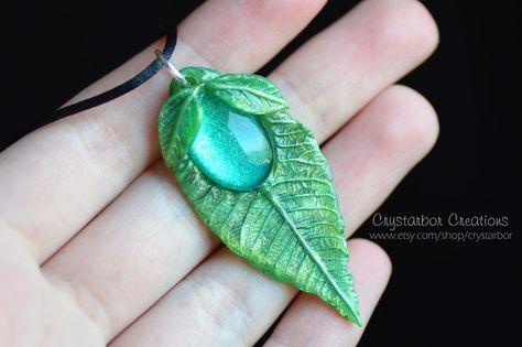 The pendant is made with polymer clay. The central cabochon is in glass and I handmade painted the back with specific paint. It has a very intense and sparkly green color. The leaf and cabochon if ... Lord Of The Rings Jewelry, Polymer Clay Beads Diy, Clay Leaf, Crea Fimo, Polymer Clay Halloween, Polymer Flowers, Polymer Clay Ring, Green Pendant, Play Clay