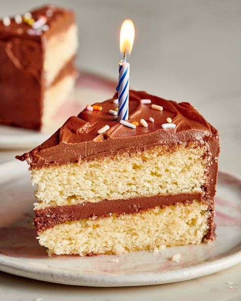 Single slice of birthday cake sits on a plate with a candle on top