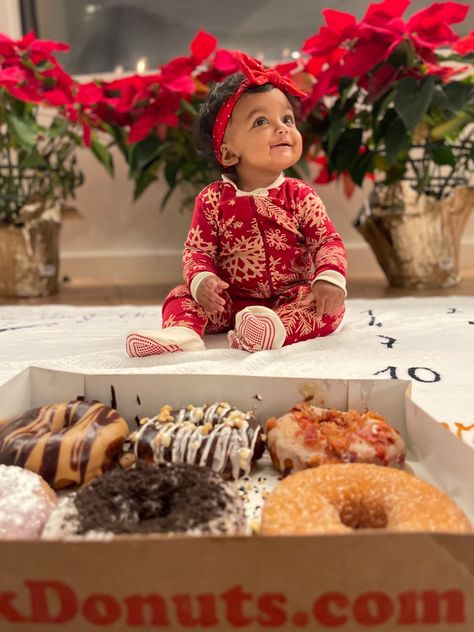 Adorable baby girl on her half birthday. She has on a red bow and a red onesie with white snowflakes printed in the center. Sitting in front of poinsettias and a fireplace. There are a dozen donuts in front of her from Duck Donuts! Half A Dozen Donuts Birthday, Half Dozen Birthday Photo, Half Dozen Photo Shoot, 6 Month Photo Shoot, 6 Month Photography, Honey Dip, 6 Month Photos, Month Pictures, Monthly Baby Pictures