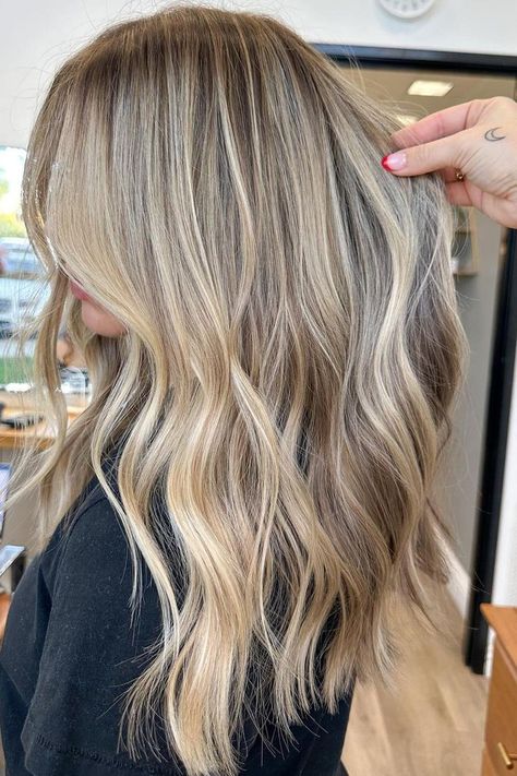 Sunkissed balayage on long layered hair creates a seamless transition from ashy brown roots to icy blonde ends, giving this look natural depth and movement. The soft waves enhance the multi-dimensional colors, ideal for adding volume to fine hair. It's a beautiful blend that works great for various occasions.  // Photo Credit: Instagram @hairby_savss Root Melt Blonde Highlights, Blonde Winter Highlights, Blonde Brown Lowlights, Blonde And Brunette Highlights, California Blonde Highlights, Blond Hair Ideas Highlights, Dirty Blonde Hair With Dimension, Bright Blonde Balayage On Brown Hair, Blonde Highlights For Winter