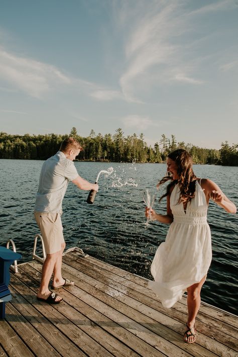 couple popped champagne at dock at the cottage Engagement Dock Photos, Summer Lake Couples Photoshoot, Cottage Couple Photoshoot, Lake Dock Engagement Pictures, Lake Engagement Party, Engagement Photos On Dock, Engagement Shoot Lake, Engagement Lake Photos, Engagement Photos Pond